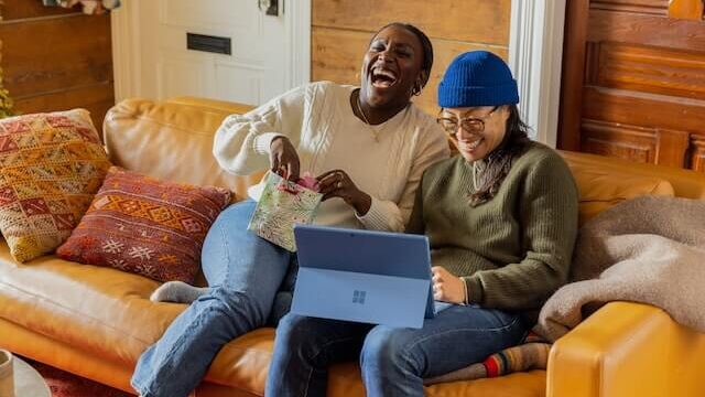 ソファーに座ってパソコンを見ながら笑っている二人の女性